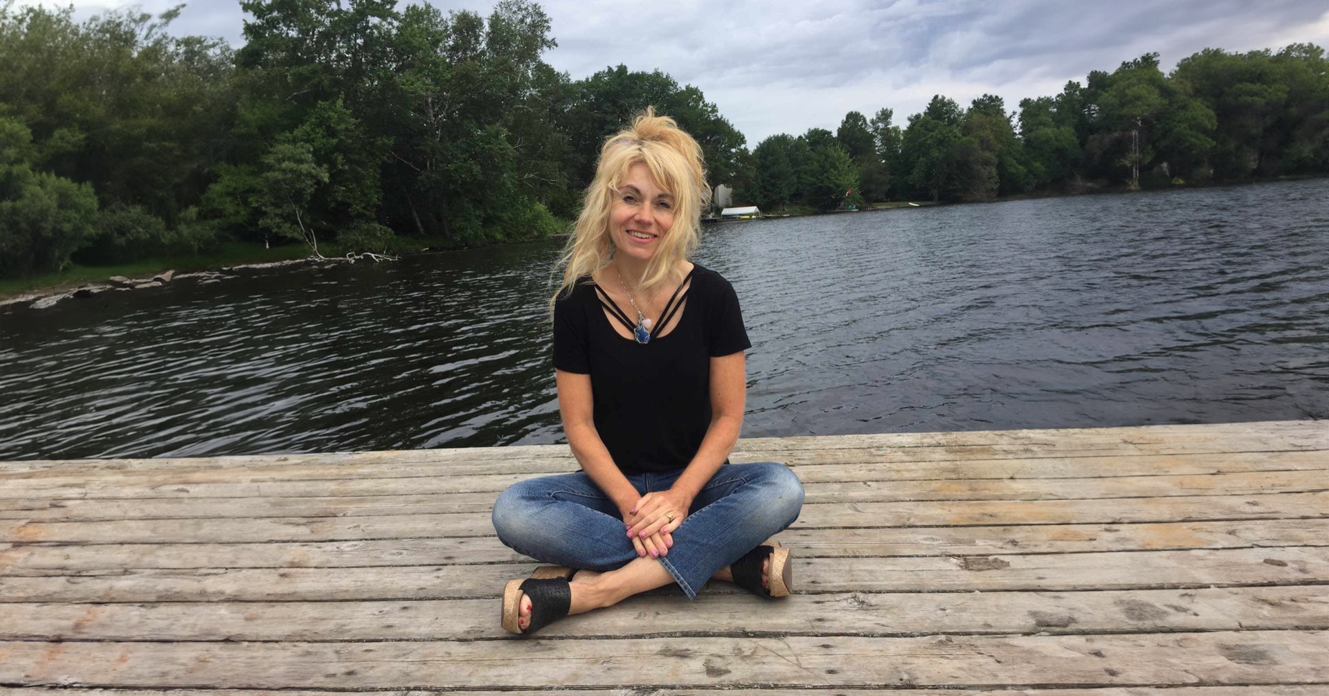 Anna Lisa Kirtan sitting on a dock by the water